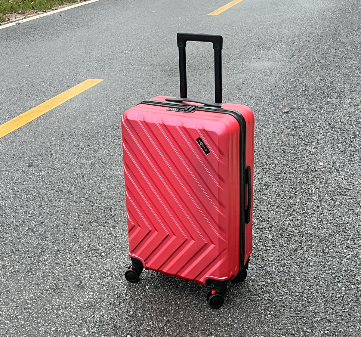 Nomado Horizon 2.0 suitcase in light pink, standing on asphalt with a yellow stripe